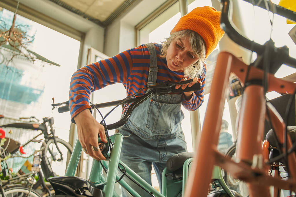 現代のワークショップで自転車を修理グレー髪白人修理男の女性。自転車サービス、修理とアップグレードの概念 - 写真・画像