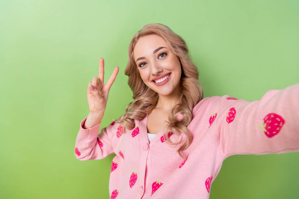 Portrait-Selfie-Foto von jungen freundlichen Mädchen zeigt V-Zeichen hallo Symbol Frieden Blogging Videoaufzeichnung isoliert auf grünem Hintergrund. - Foto, Bild