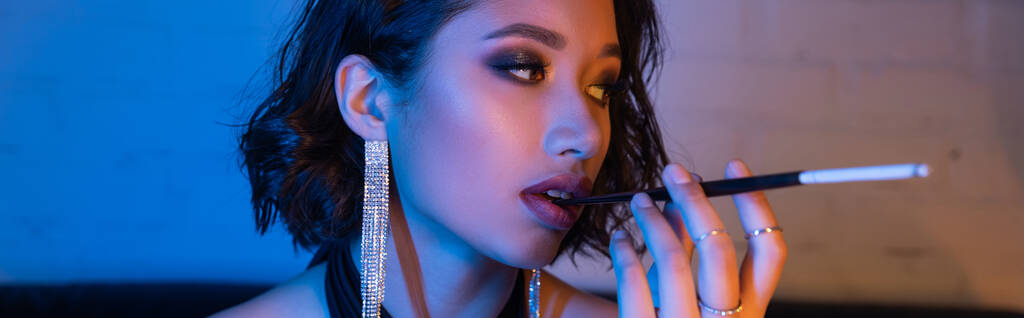 Trendy ázsiai nő arckép tartja cigaretta szájfeltéttel éjszakai klub neon fény, banner - Fotó, kép