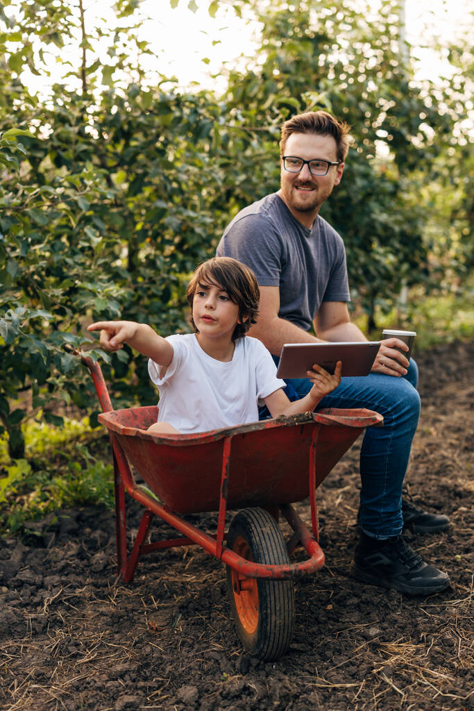 Kaukasier und sein Sohn spielen im Obstgarten. - Foto, Bild