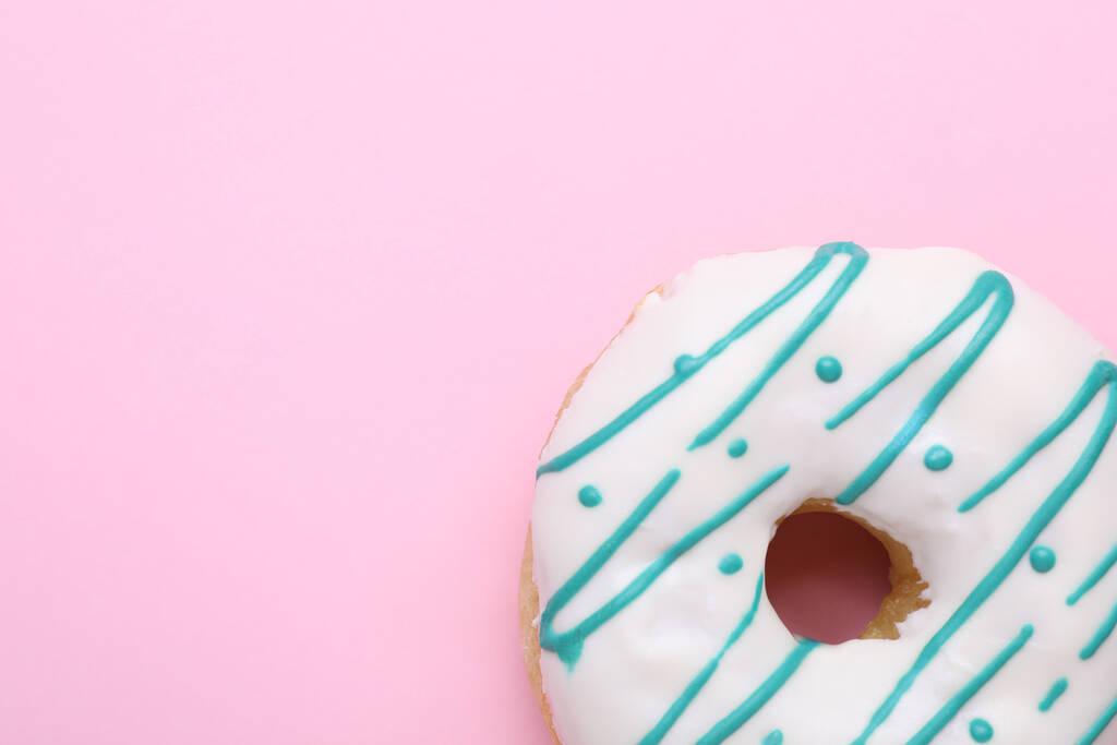 Lekker geglazuurde donut op roze achtergrond, bovenaanzicht. Ruimte voor tekst - Foto, afbeelding