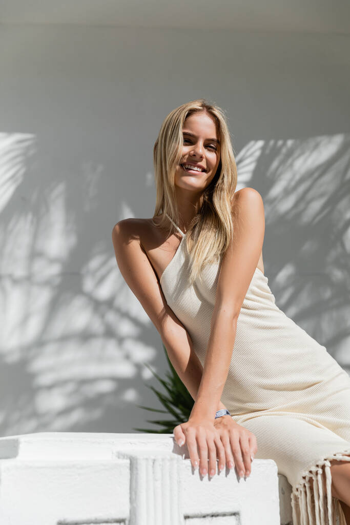 Młoda i piękna blondynka w białej sukience uderza w pozę do zdjęcia w słoneczny dzień w Miami. - Zdjęcie, obraz