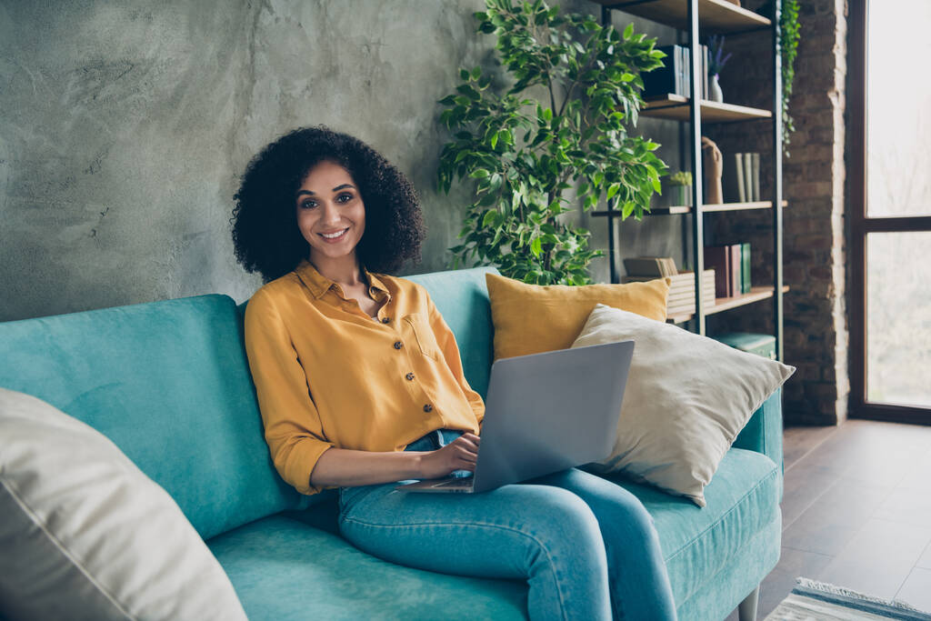 Фото улыбающейся милой ассистентки в рубашке, сидящей на диване и чатящей телеграммой в facebook Instagram на рабочем месте. - Фото, изображение