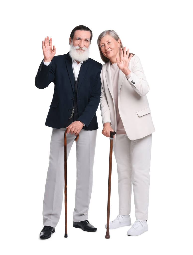 Uomo anziano e donna con bastoni da passeggio che ondeggiano su sfondo bianco - Foto, immagini