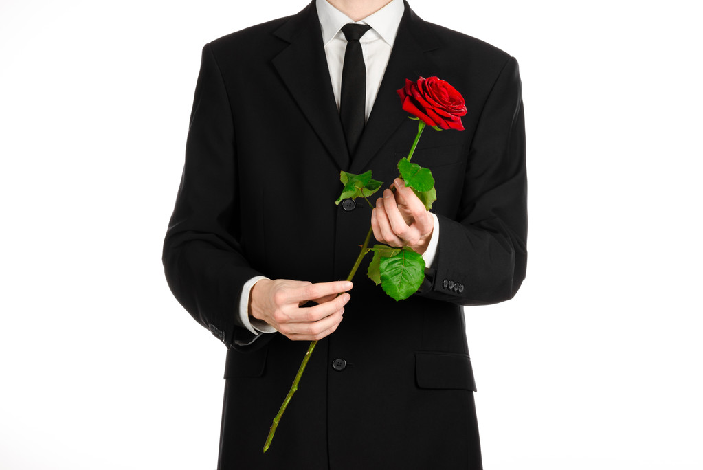 Valentine's Day and Women's Day theme: man's hand in a suit holding a red rose isolated on white background in studio - Photo, Image