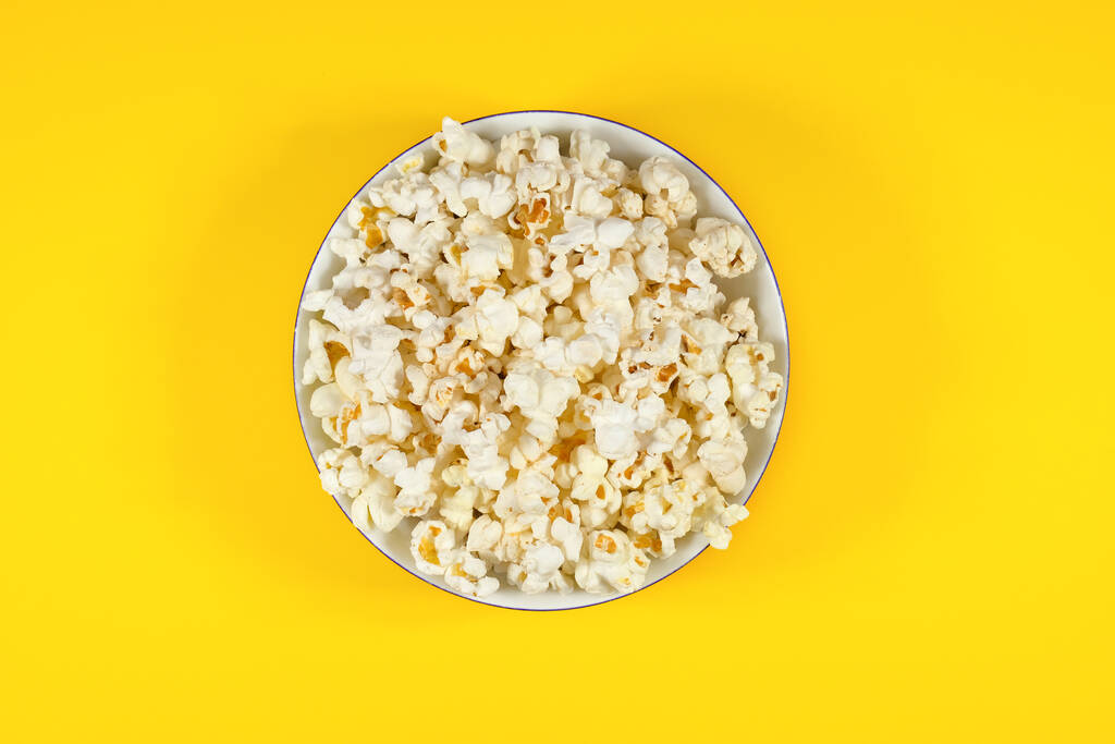 Teller mit frischem Popcorn auf gelbem Hintergrund. Kino- und Unterhaltungskonzept. Ansicht von oben. - Foto, Bild