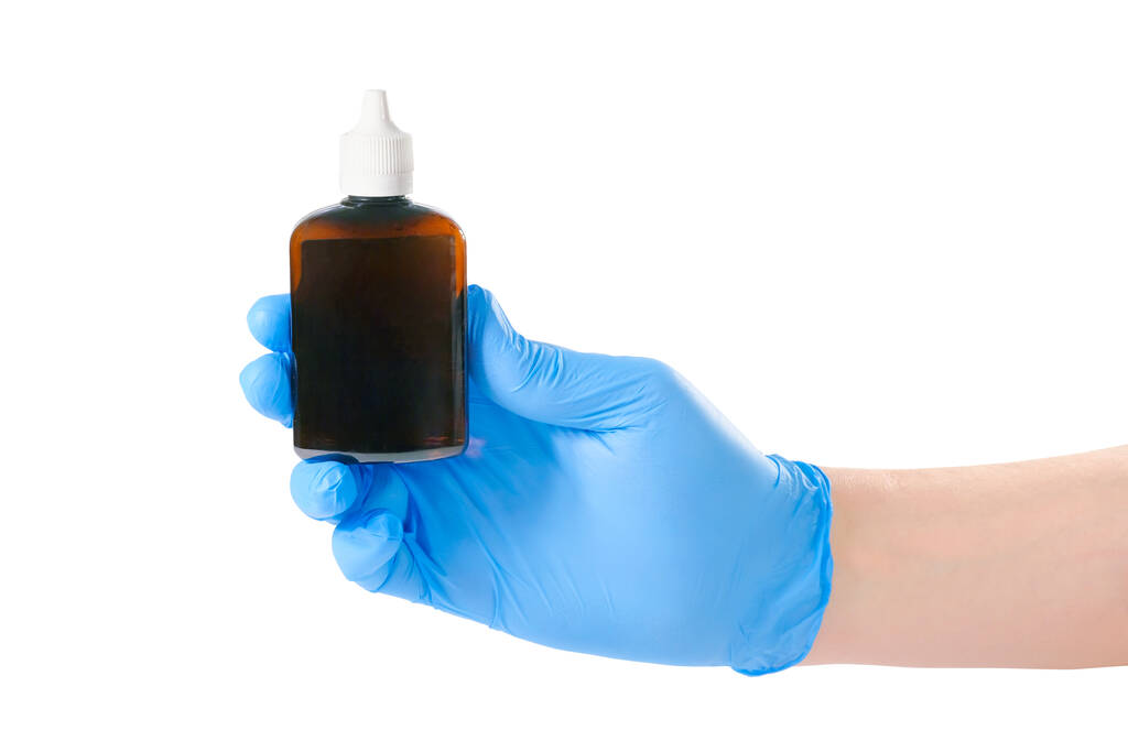 Ένα χέρι σε ένα μπλε ιατρικό γάντι κρατά ένα μπουκάλι εμβόλιο ή φάρμακο, απομονωμένο σε λευκό. - Φωτογραφία, εικόνα