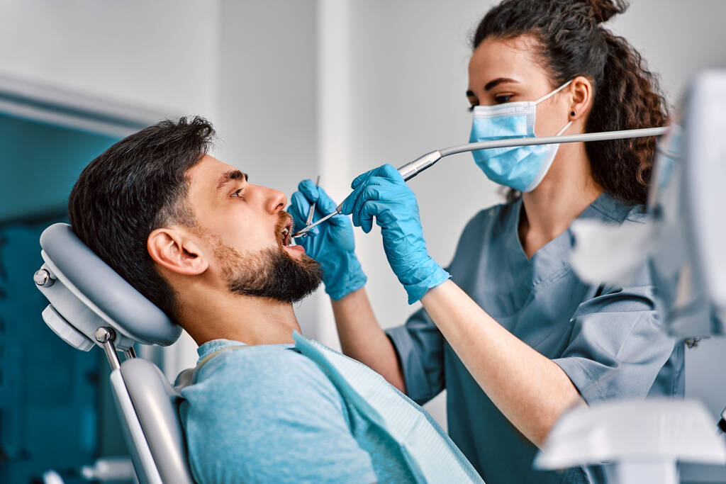 Zahnmedizin, Medizin. Eine Zahnärztin in Maske behandelt die Zähne einer Patientin. - Foto, Bild