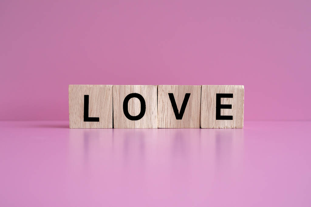Tahta bloklar pembe arkaplan üzerinde "Love" metnini oluşturur. - Fotoğraf, Görsel
