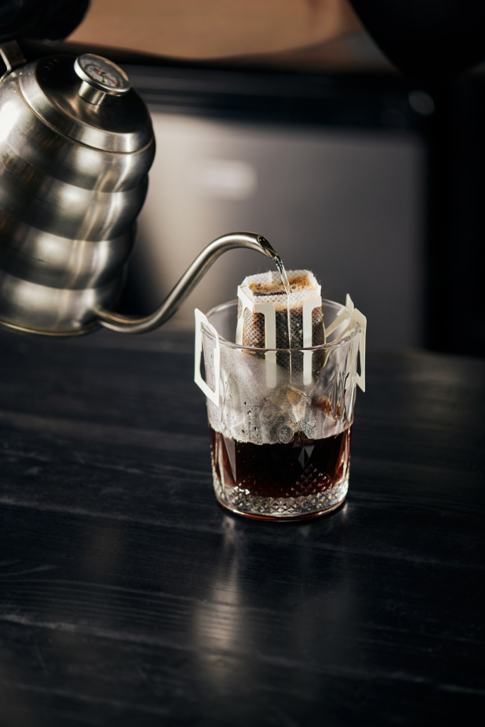 brebaje alternativo, agua hirviendo vertiendo en vidrio con café en bolsa de filtro, espresso vertido - Foto, imagen