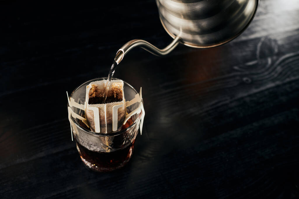  przelewanie espresso, nalewanie wrzącej wody z czajnika kroplowego do szklanki z kawą w worku filtracyjnym - Zdjęcie, obraz