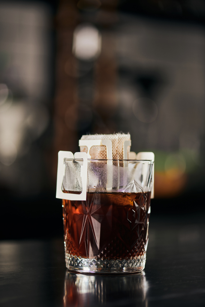 bicchiere con caffè macinato in sacchetto filtro carta su contatore nero, espresso aromatico, metodo alternativo - Foto, immagini
