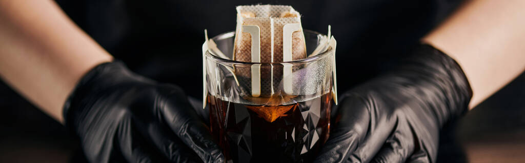barista in zwarte handschoenen voor het bereiden van koffie in kristalglas en papieren filterzak, druppelmethode, banner - Foto, afbeelding