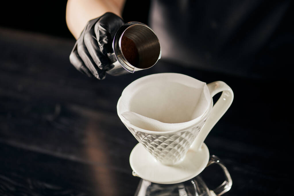 V-60 style espresso method, barista holding jigger with fine ground coffee near ceramic dripper  - Photo, Image