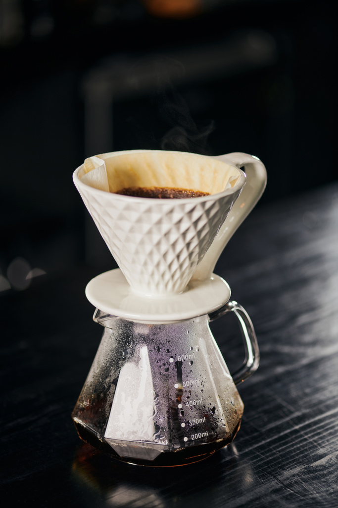 ceramic dripper with pour-over coffee on glass pot in cafe on black table, alternative V-60 style  - Photo, Image