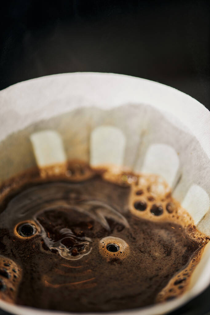 vista ravvicinata del caffè aromatico appena preparato con schiuma in sacchetto filtro di carta, espresso in stile V-60 - Foto, immagini