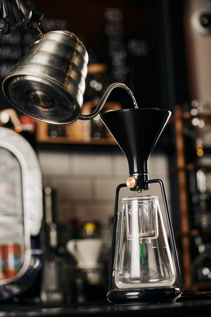 μερική άποψη του barista ρίχνει βραστό νερό σε συναρμολογημένη καφετιέρα siphon στην καφετέρια - Φωτογραφία, εικόνα