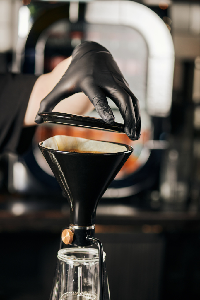 przycięty widok baristy w czarnej rękawicy przygotowującej espresso i otwierający ekspres do kawy z syfonem  - Zdjęcie, obraz