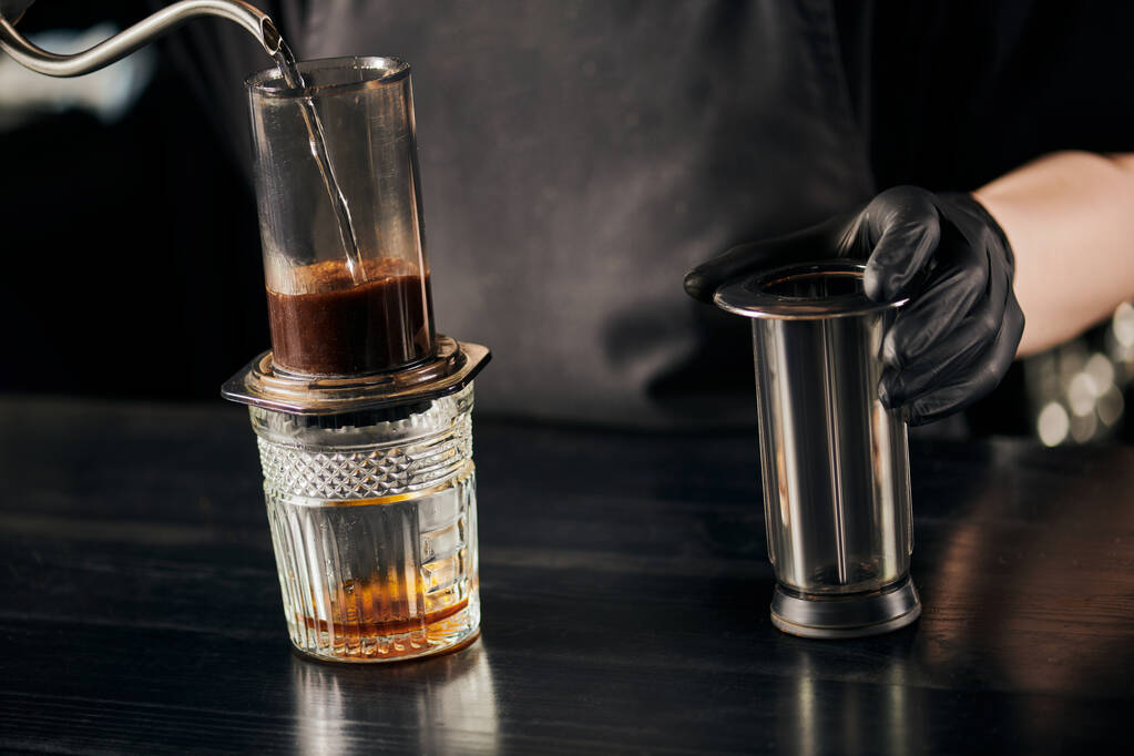 partial view of barista pouring boiling water in aero press coffee maker, alternative espresso method - Photo, Image