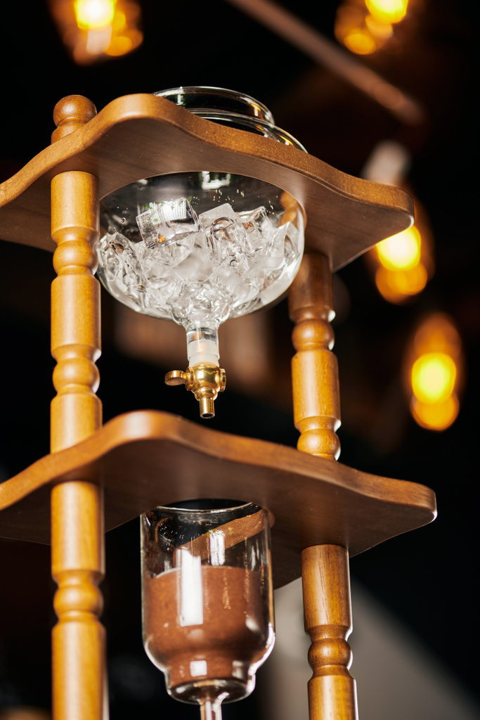 lage hoek uitzicht op koude druppelkoffiezetapparaat met ijsblokjes en gemalen koffie, alternatieve espresso brouwsel - Foto, afbeelding