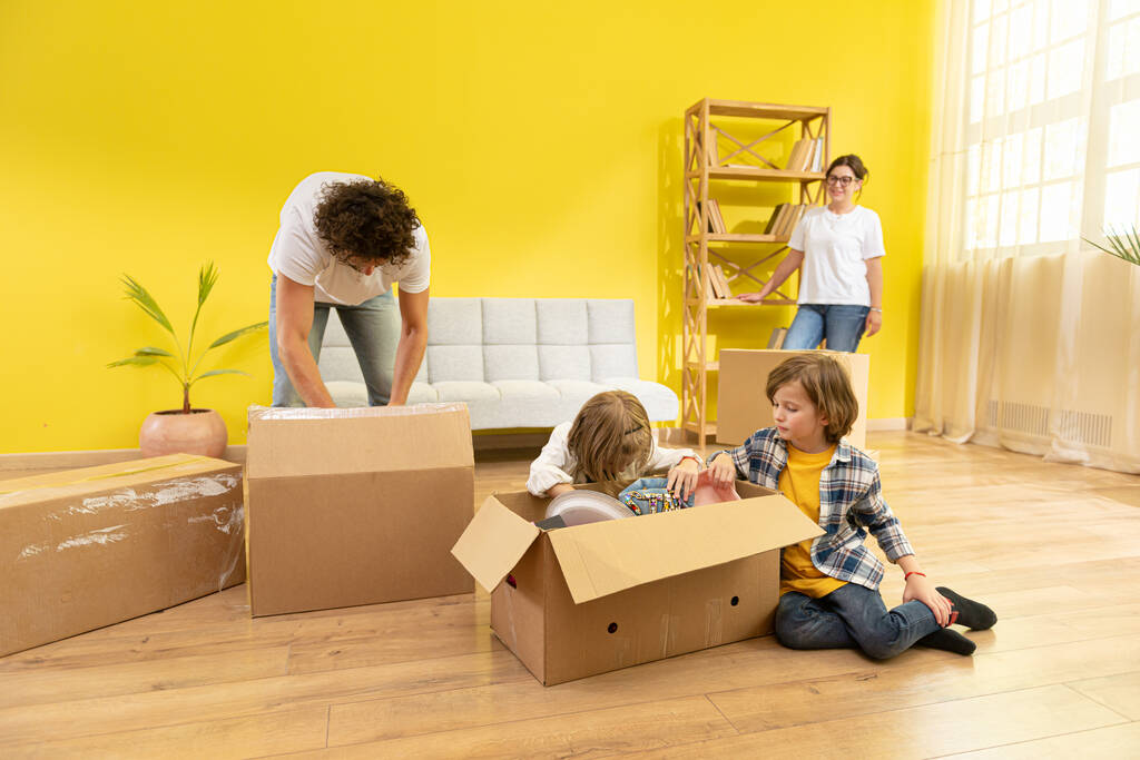 Na frente da câmera, duas crianças felizes e seus pais se movendo na nova casa, eles aproveitam o tempo juntos jogando Rock Paper Scissors enquanto se sentam no novo sofá. Família - Foto, Imagem