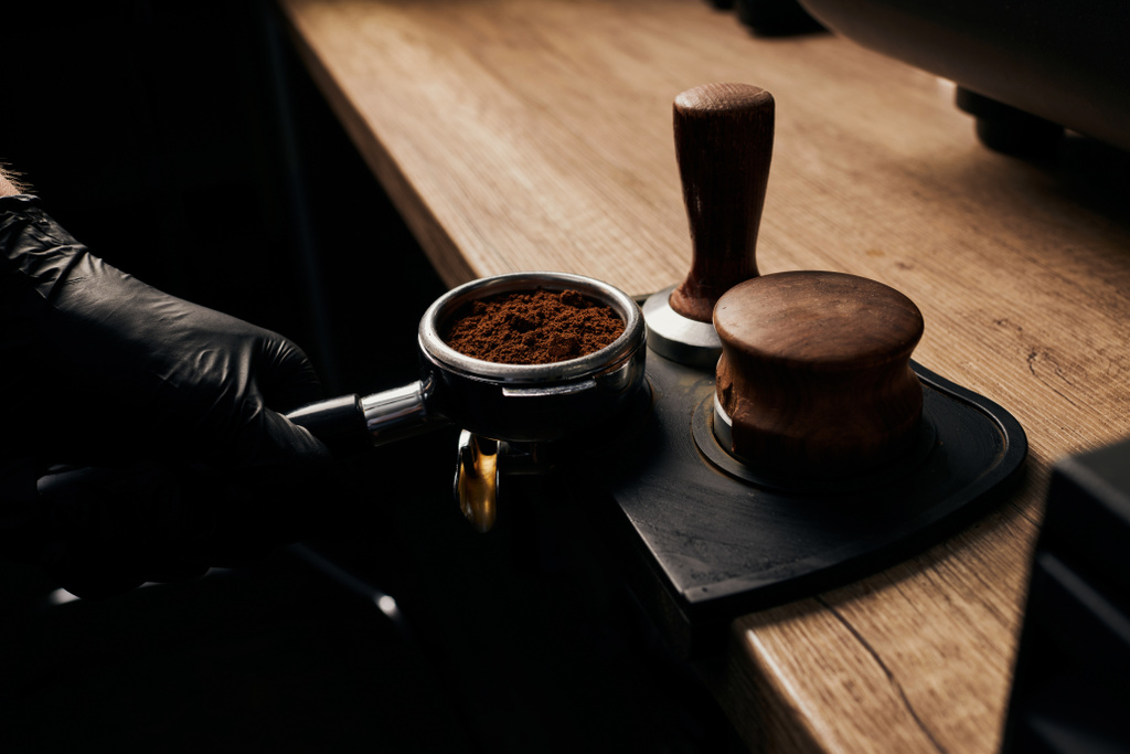 barista holding portafilter with grinded coffee, tamper, wooden table, cafe, alternative brew - Фото, изображение