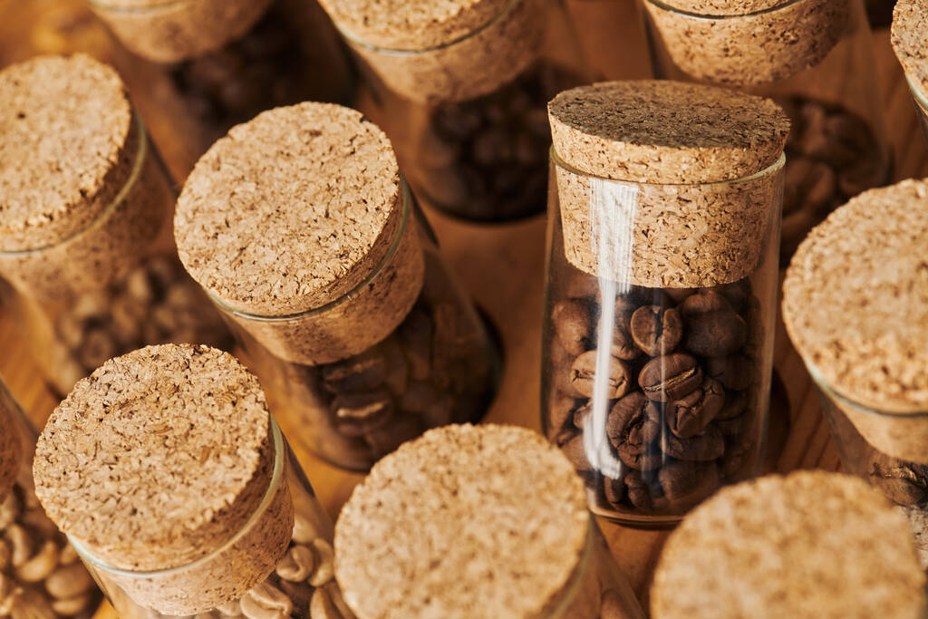 granos de café en frascos de vidrio con corcho, tostado, cafeína y energía, fondo de café, vista superior - Foto, imagen