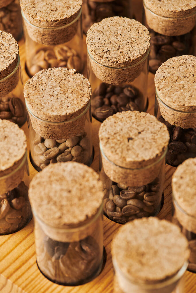 granos de café en frascos de vidrio con corcho, diferentes tostados, cafeína y energía, fondo de café  - Foto, imagen