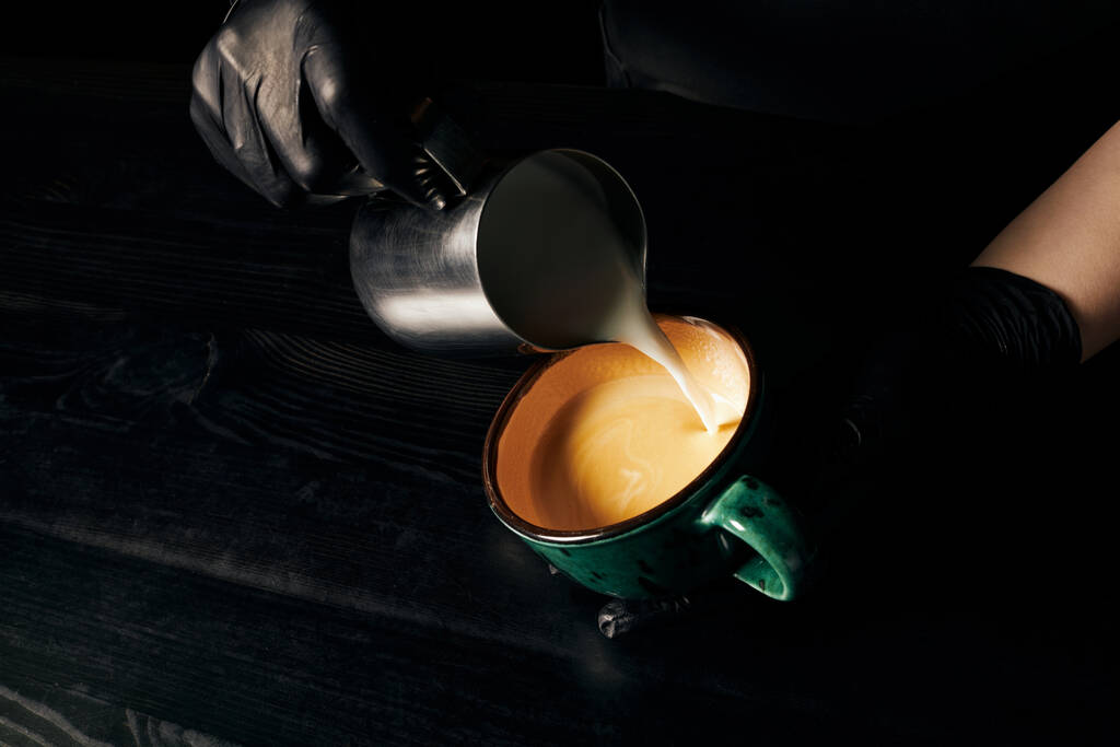 Barista hält Kanne, gießt Milch, bereitet Cappuccino, aromatischen Espresso, Latte Art, beschnitten  - Foto, Bild
