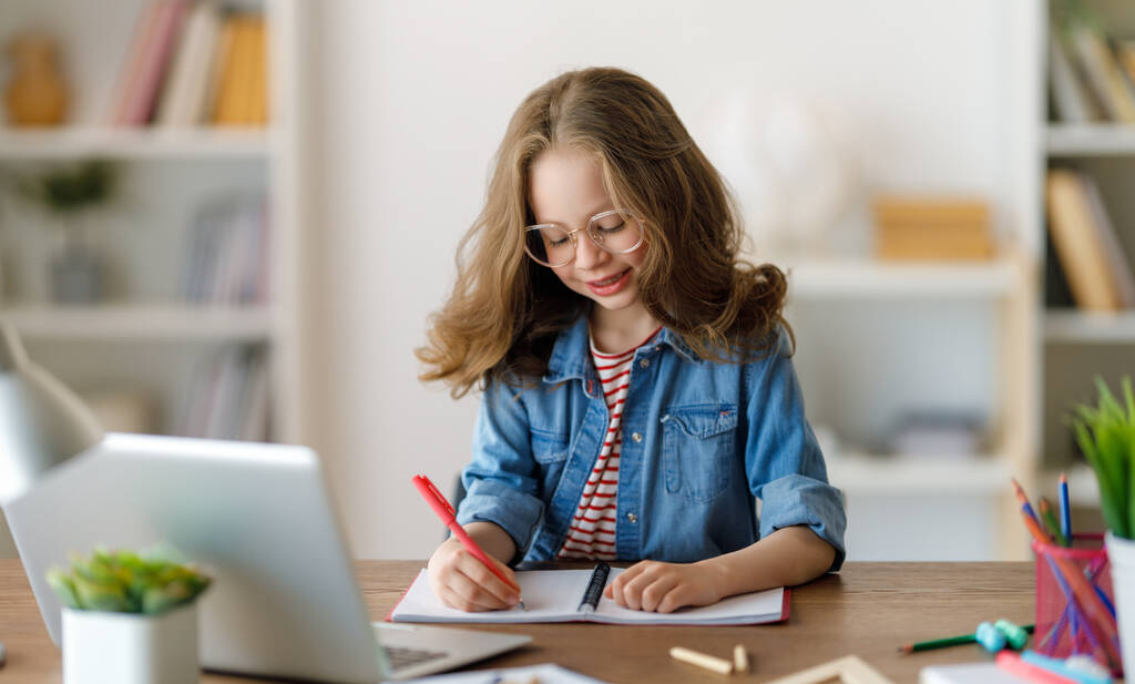 De vuelta a la escuela. El niño feliz está sentado en el escritorio. Chica haciendo deberes o educación en línea. - Foto, imagen