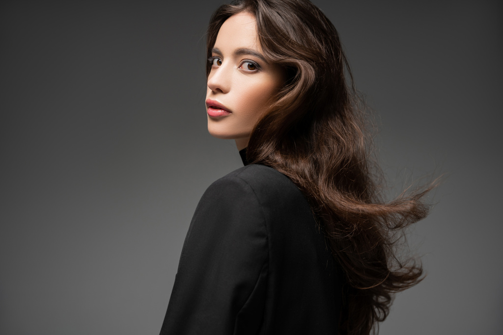 Divatos ázsiai modell smink és frizura pózol fekete kabát elszigetelt szürke - Fotó, kép
