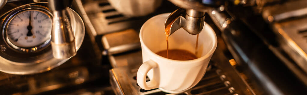 Kahve makinesinden beyaz bardağa dökülen kahve manzarasını kapatın. Kafede güneş ışığı, pankart. - Fotoğraf, Görsel