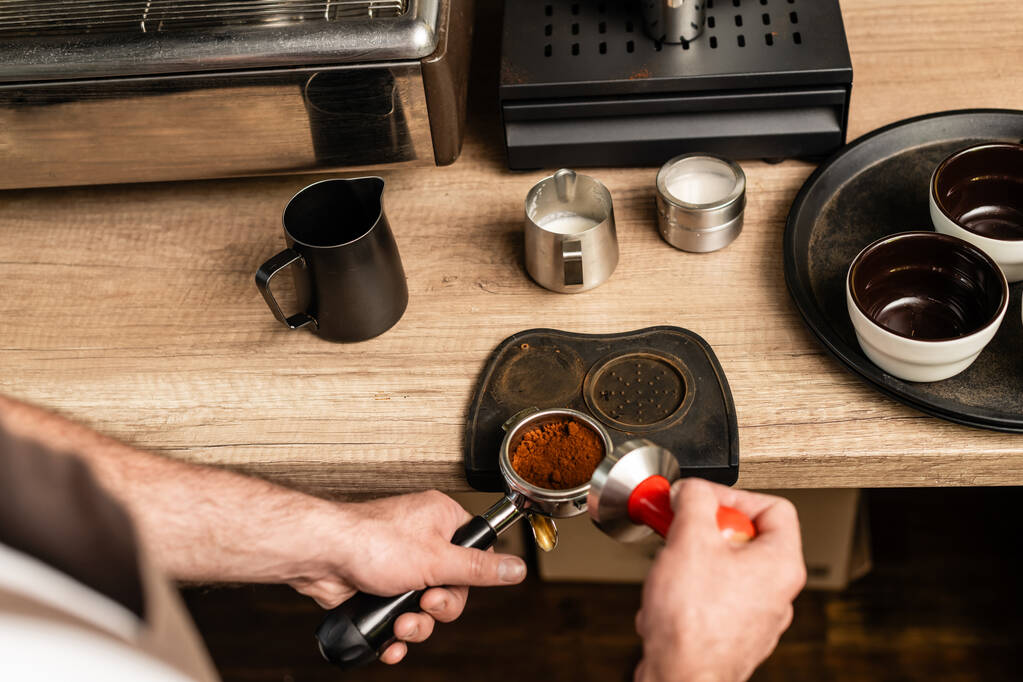 hoge hoek uitzicht op barista holding pers en houder met koffie in de coffeeshop - Foto, afbeelding