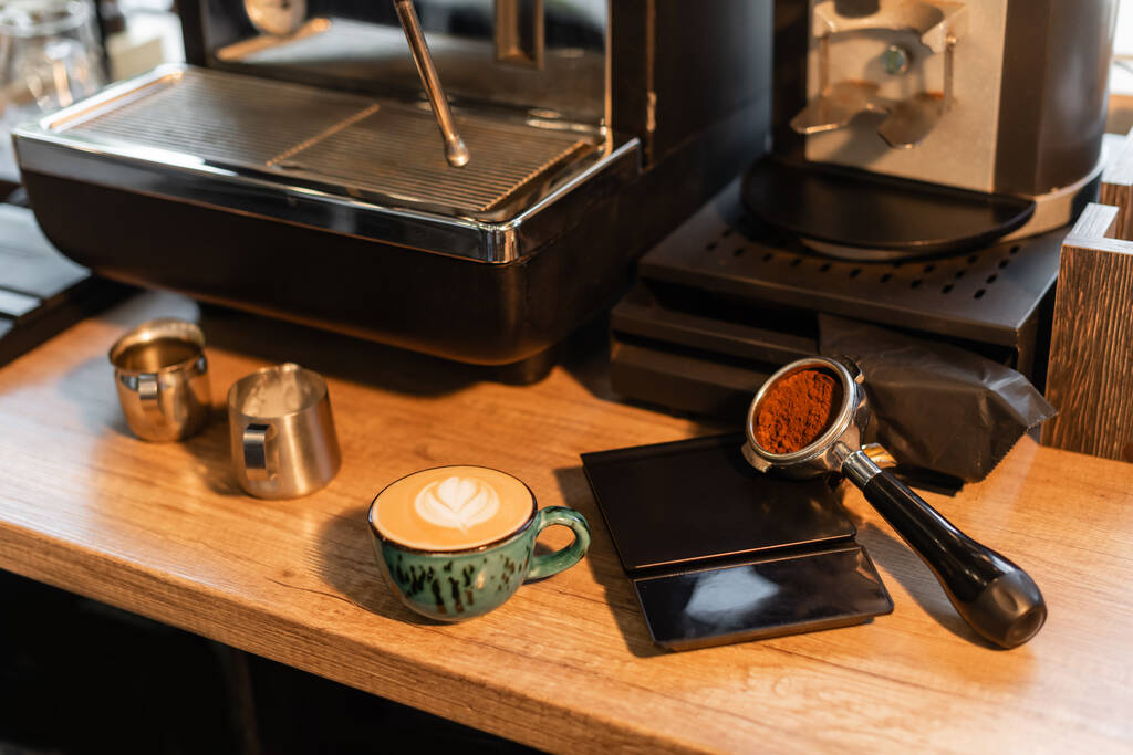 καφέ στη θήκη κοντά φλιτζάνι καπουτσίνο στο εργαστήριο στην καφετέρια - Φωτογραφία, εικόνα