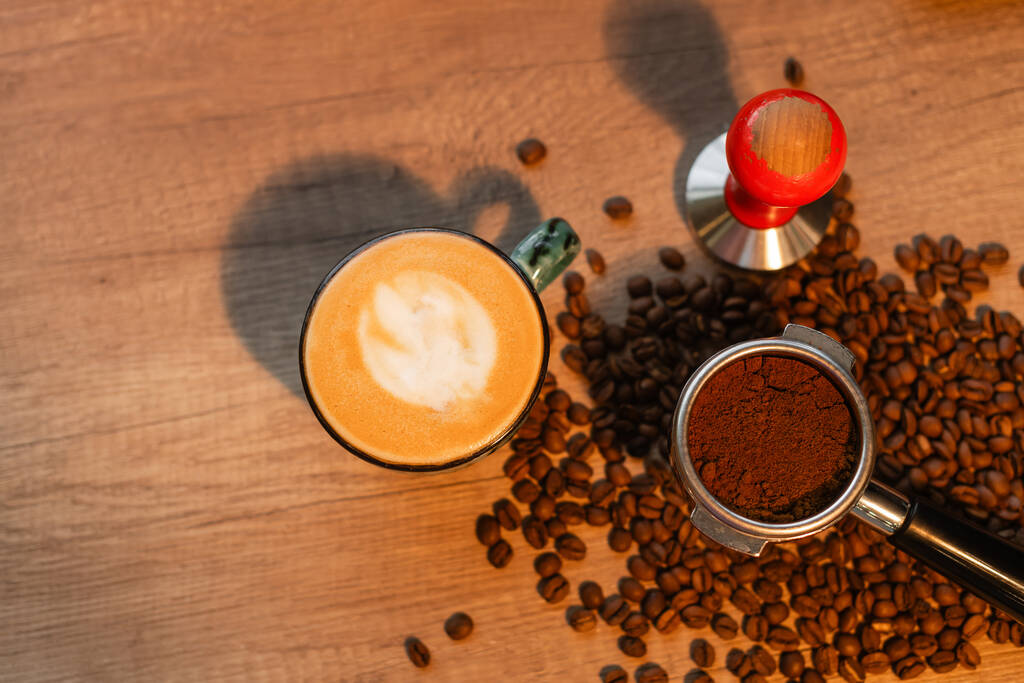 top view of cappuccino, press and coffee beans with lighting in coffee shop - Photo, Image