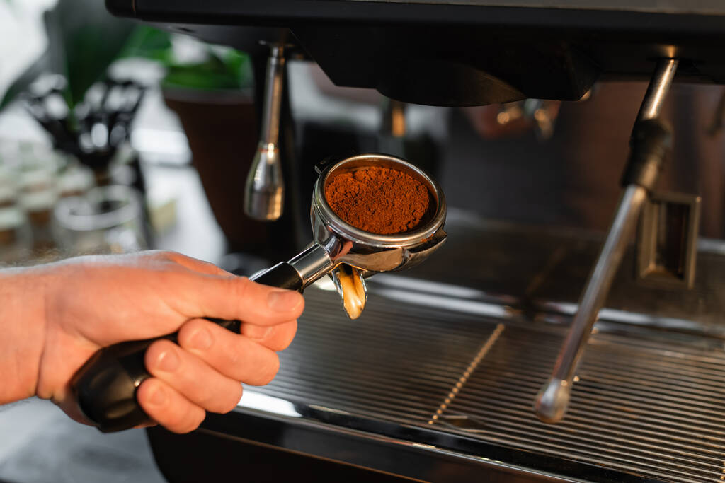 καλλιεργημένη άποψη του κατόχου barista εκμετάλλευση με καφέ κοντά θολή μηχανή καφέ στο καφέ - Φωτογραφία, εικόνα