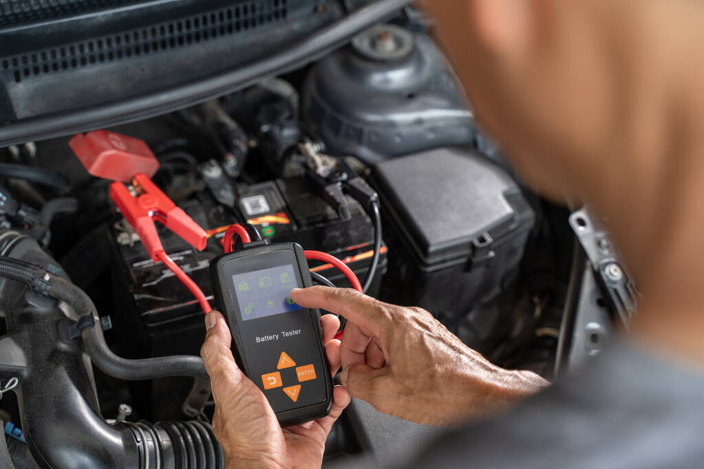Fermez les mains d'un mécanicien automobile masculin à l'aide d'un testeur de batterie pour tester l'état de la batterie de la voiture - Photo, image