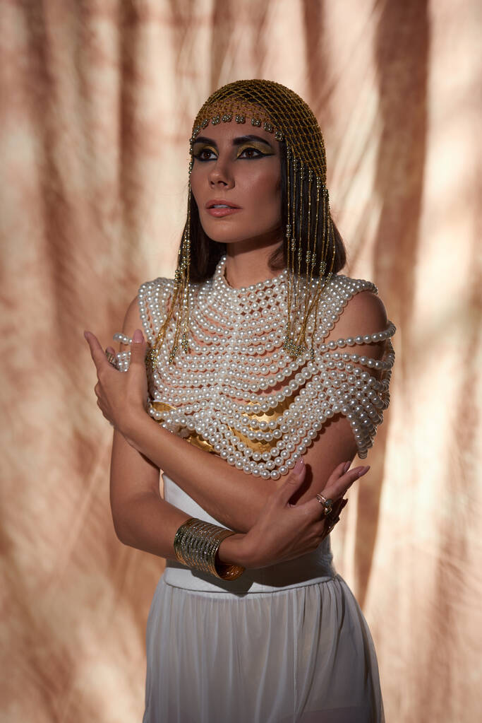 Portrét brunetky ženy v perleťovém svršku a egyptském vzhledu pózující na abstraktním pozadí - Fotografie, Obrázek