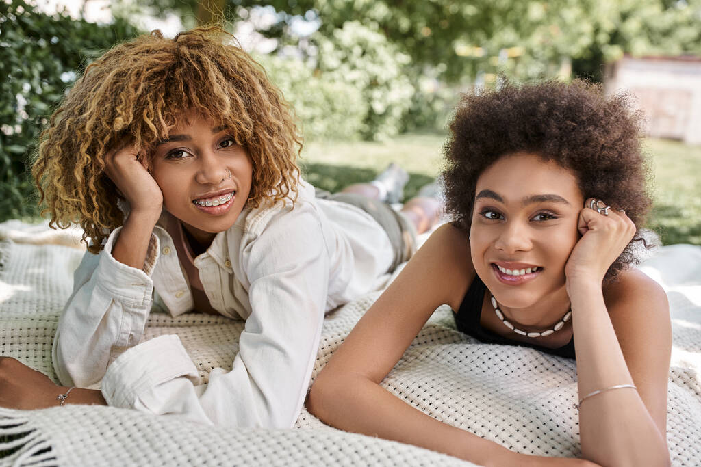 loisirs dans le parc d'été, heureuses copines afro-américaines allongées sur la couverture et regardant la caméra - Photo, image