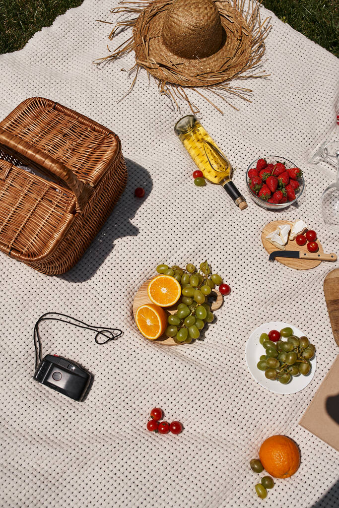 концепция пикника, виноград, клубника, помидоры черри, апельсин, вино, корзина, соломенная шляпа, вид сверху - Фото, изображение