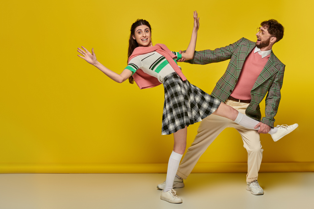 hombre alegre en gafas atrapando a la mujer que cae, pareja joven, divertido, fondo amarillo, emocional - Foto, imagen