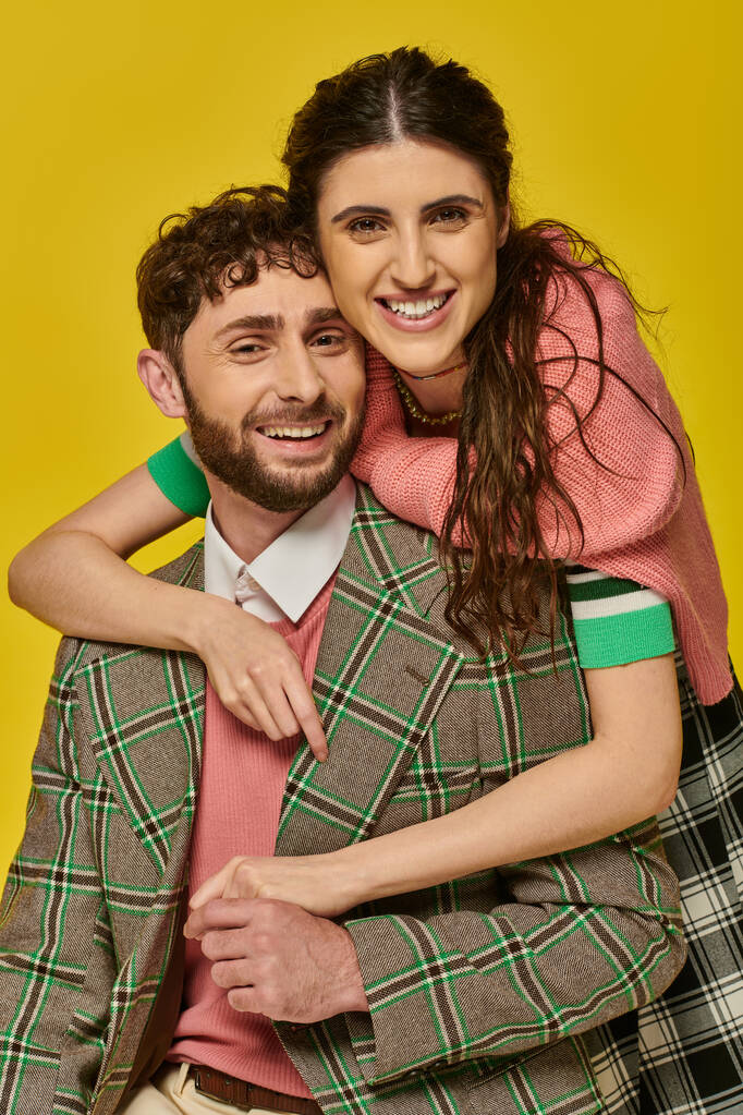 cheerful woman hugging bearded man, in blazer, yellow backdrop, college outfits, happy students - Photo, Image