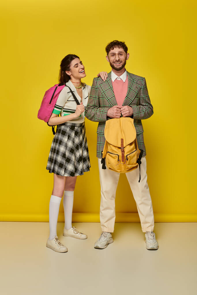 students standing with backpacks, looking at camera, smiling, yellow backdrop, academic wear, style - Photo, Image