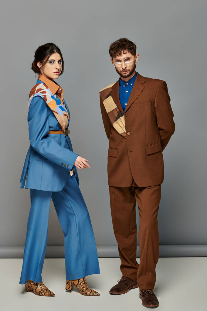 Trendpaar, Mode-Shooting, Mann und Frau in Anzügen posieren vor grauem Hintergrund, braun, blau, Stil - Foto, Bild