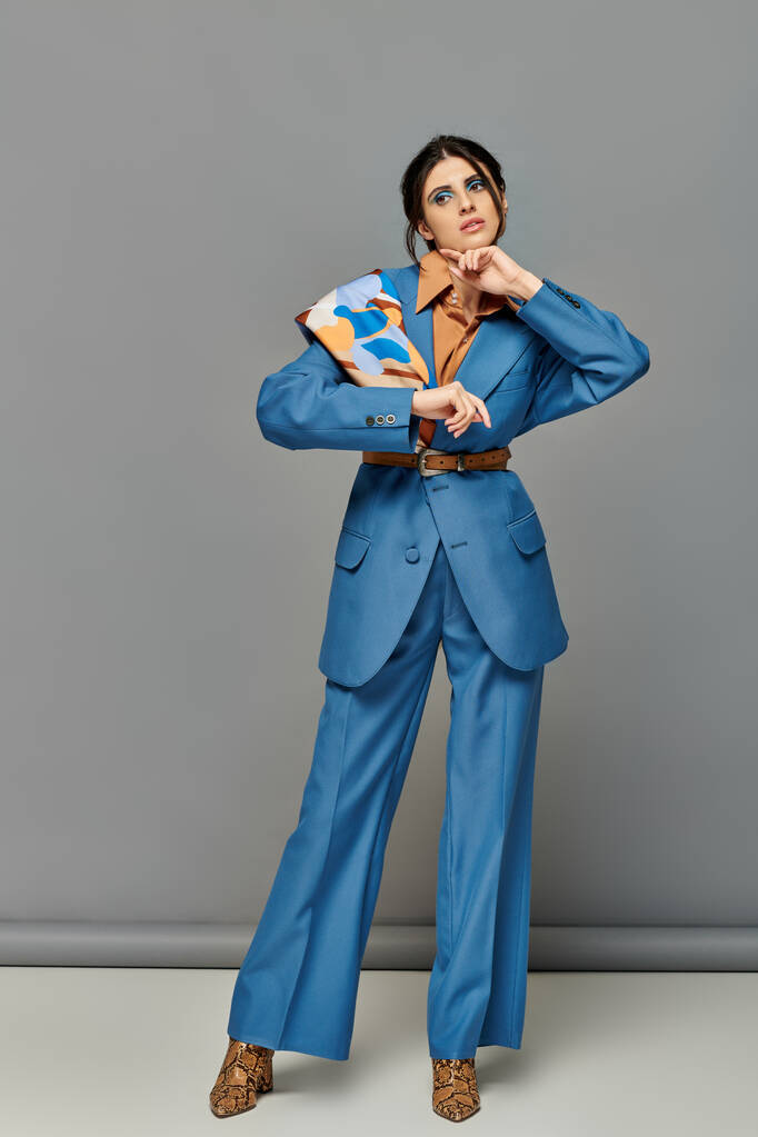 schöne Frau mit kühnem Make-up, Modell im blauen Maßanzug, formelle Kleidung, grauer Hintergrund - Foto, Bild