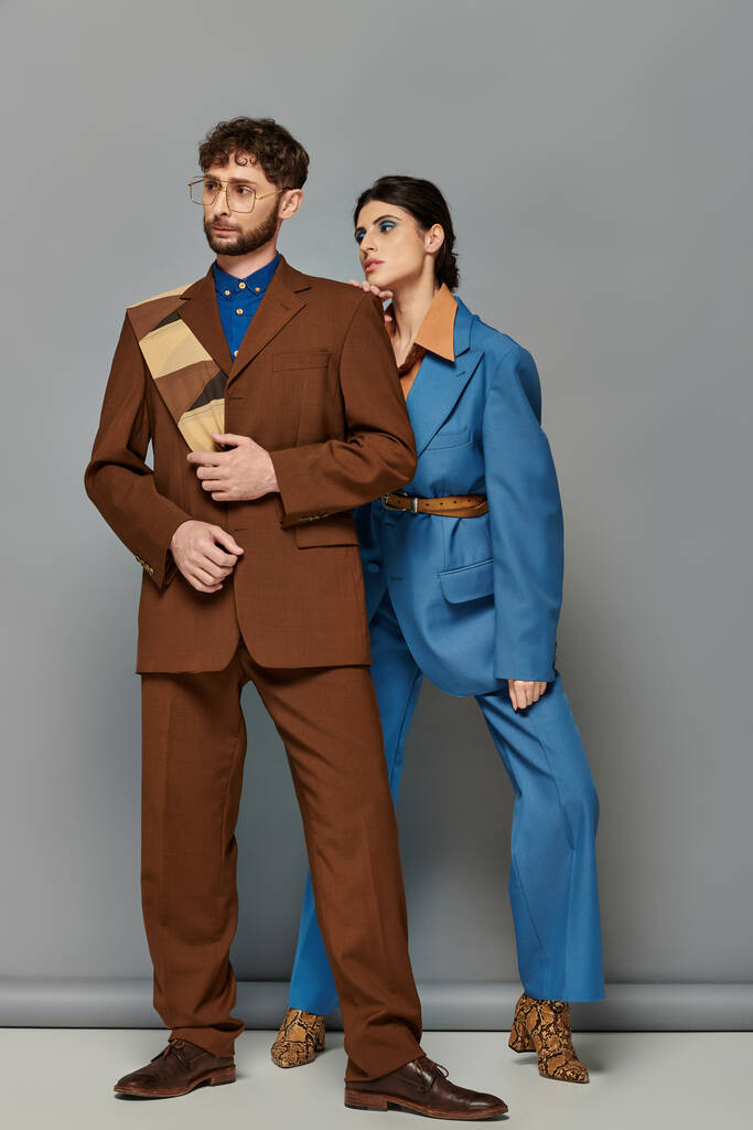 modelos de moda en trajes posando sobre fondo gris, elegante hombre y mujer en traje formal a medida - Foto, Imagen
