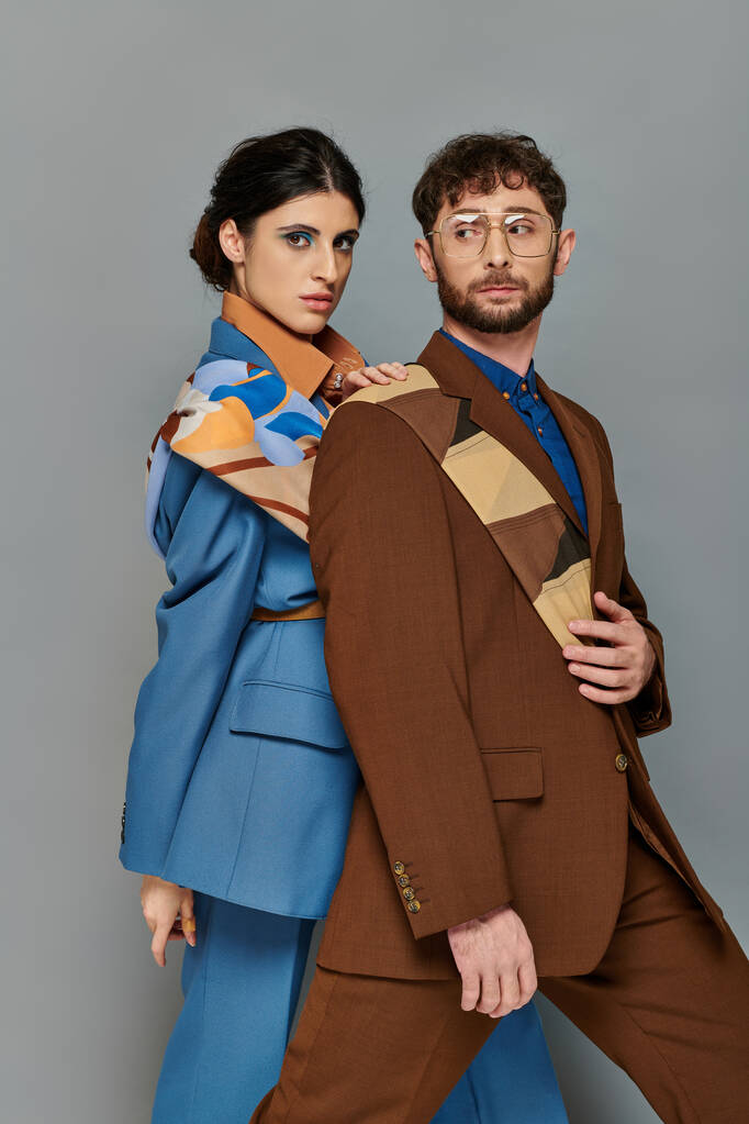stilvolles Paar in Anzügen posiert auf grauem Hintergrund, elegantem Stil, fettem Make-up, Mann und Frau - Foto, Bild