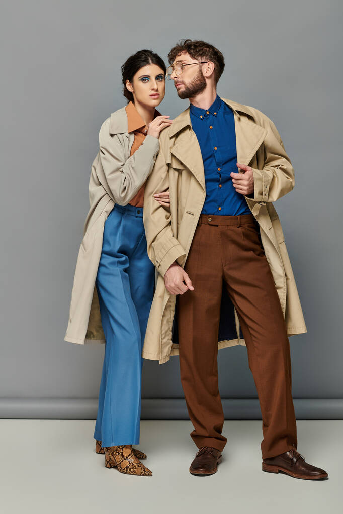 outerwear, couple in trench coats, fashion shot, stylish man and woman, grey background, trends - Photo, Image