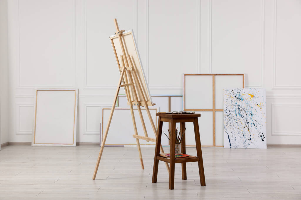 Wooden easel with canvas and painting supplies in artist's studio - Photo, Image