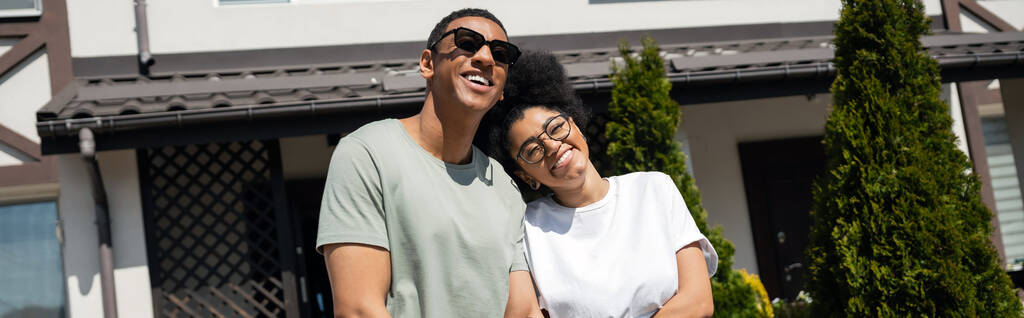 mosolygós afro-amerikai pár áll közel az új ház a háttér szabadban, banner - Fotó, kép
